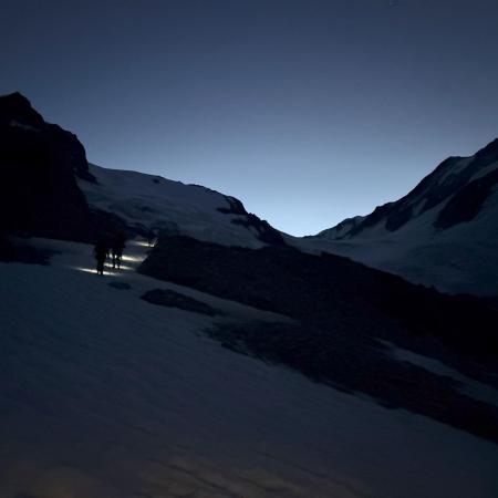 © John Lorayna – Stirnlampen durchdringen während des Aufstiegs die Dunkelheit vor der Morgendämmerung.